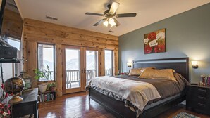 A bedroom with a large bed, wooden floor, a ceiling fan, a balcony with a view, and a painting on the wall. - Mountain Cabin/Pine Flat Lake/Kings Canyon/Sequoia National Park/Yosemite (Piedra)