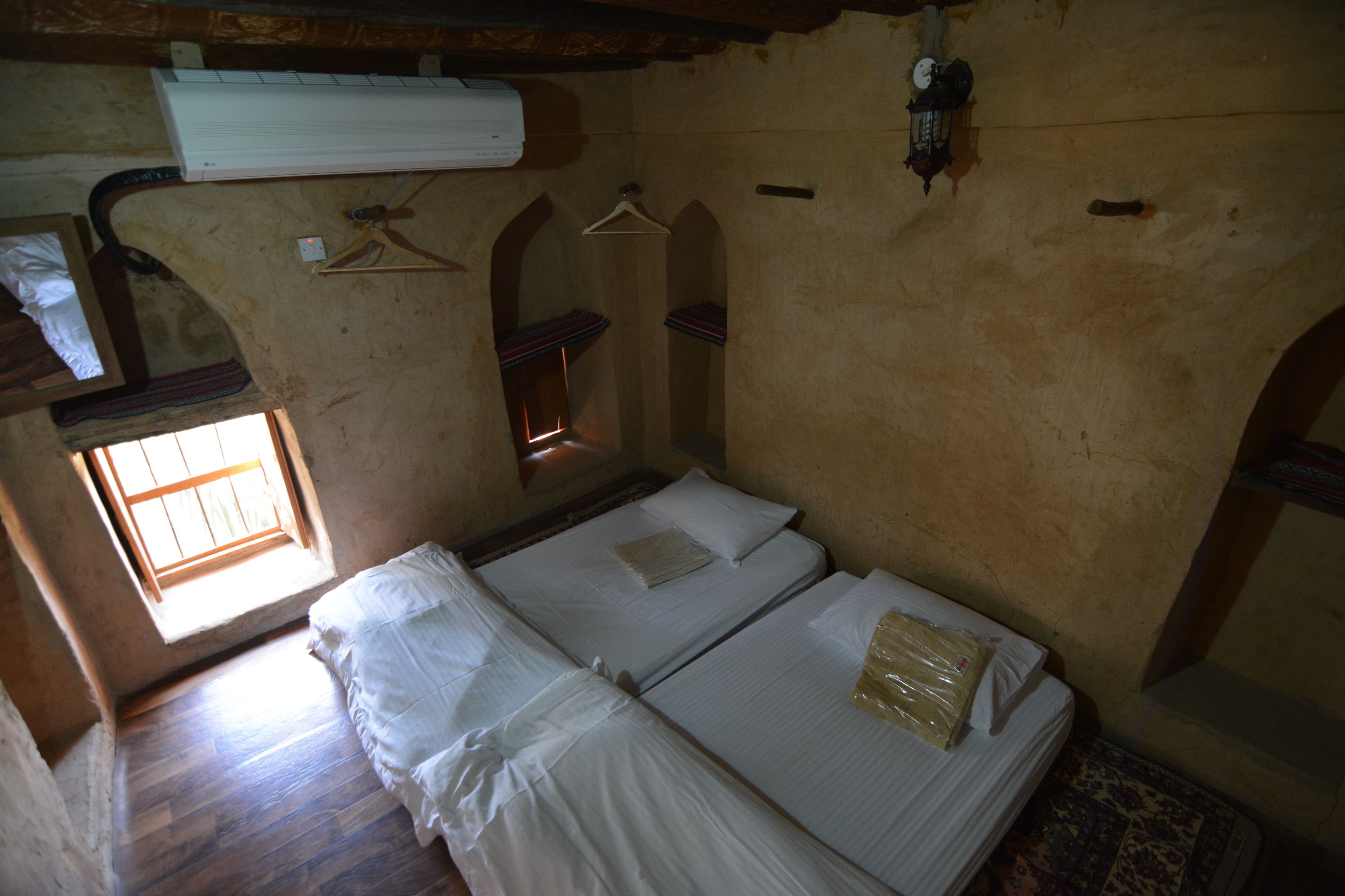 A room with two beds, a window, and a hanging light fixture.