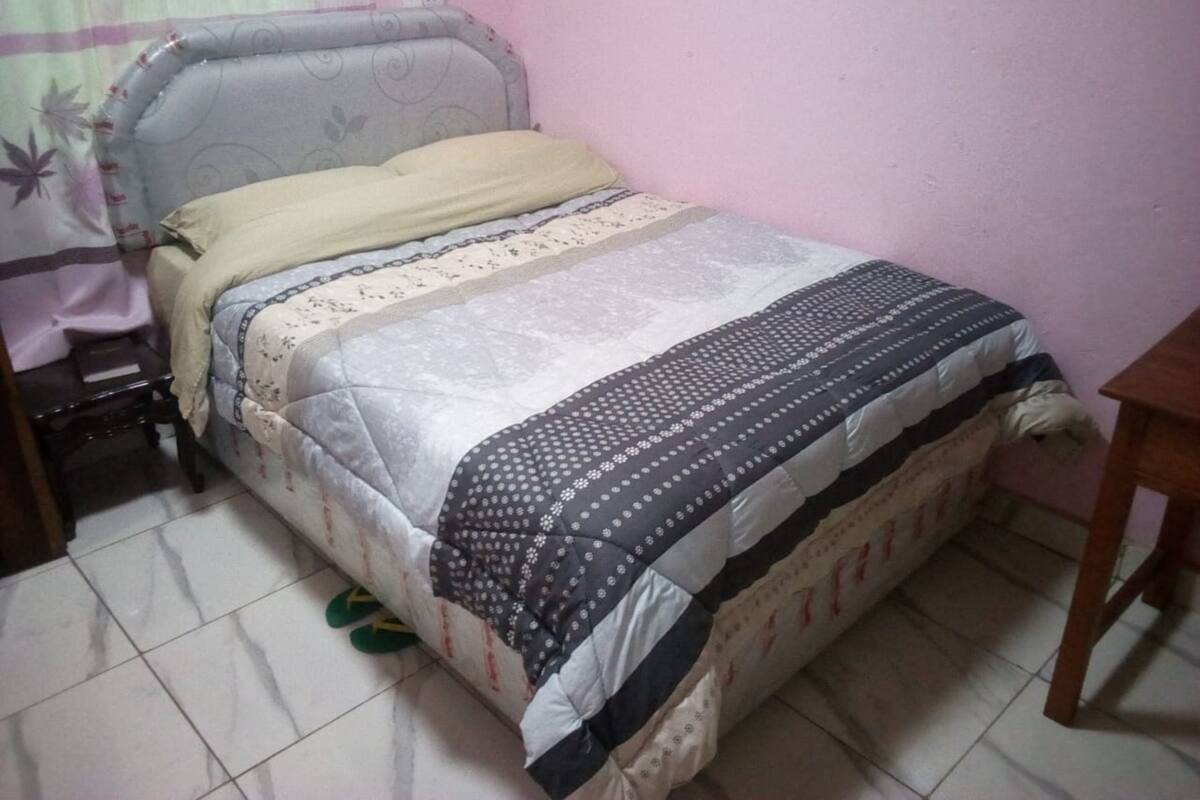 Ein Schlafzimmer mit einem Bett, einem Nachttisch, einem Sessel und einem Holztisch.