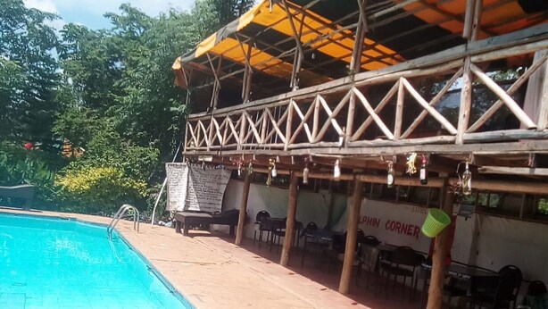 A pool area with a covered seating area and a sign that reads "Dolphin Corner." - Mark5 Resort (Njumbi)