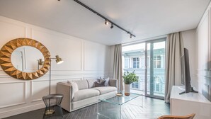 A modern living room with a sofa, a glass coffee table, a round mirror, a floor lamp, and a television. - Greenmarket 701 - Adults Only (Cape Town)