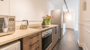 A modern kitchen with a microwave, kettle, and a vase of flowers on the counter. - Greenmarket 701 - Adults Only (Cape Town)
