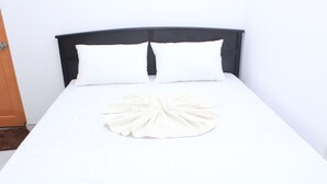 A neatly made bed with white linens and a decorative white towel on the bedspread.