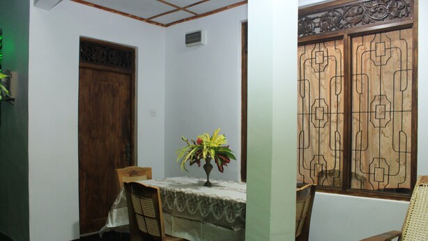 A dining area with a table set for two, a wooden door, and a window with decorative lattice.