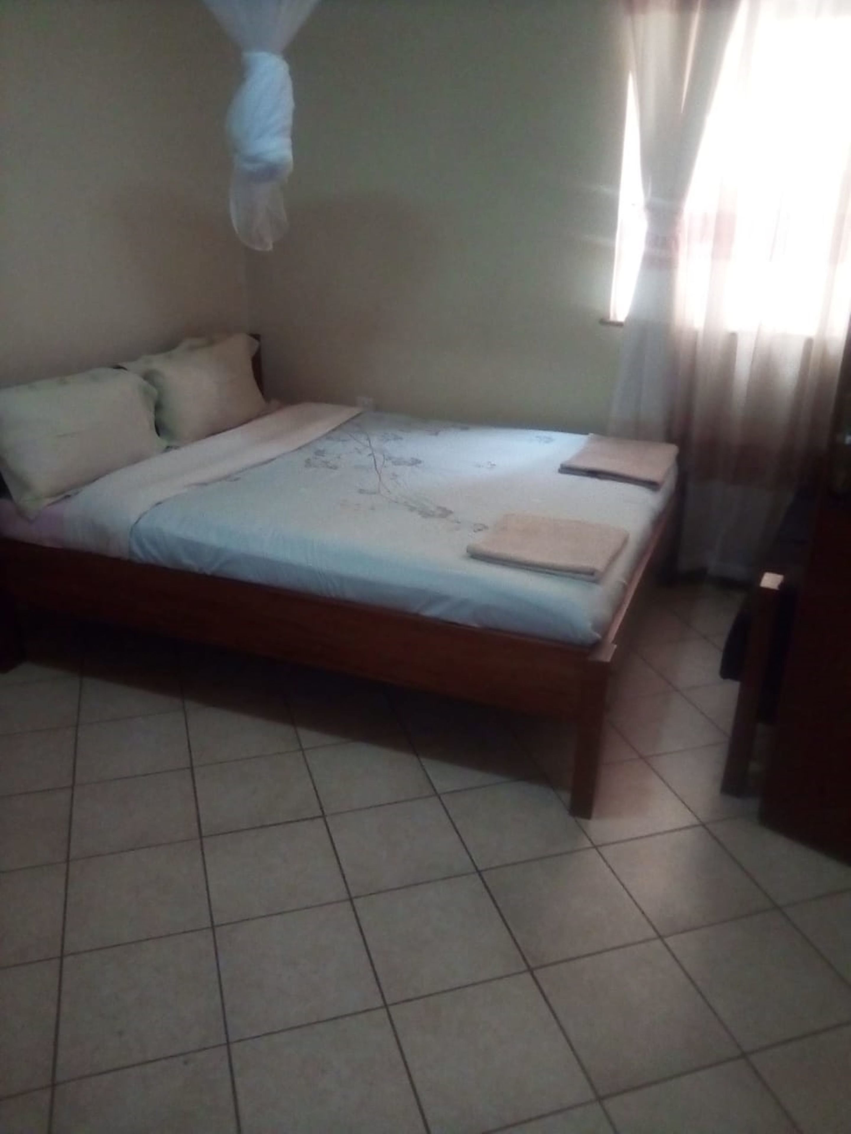 Quarto com cama, almofadas e mosquiteiro.