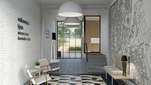 Ein modernes Interieur mit einer weißen Ziegelwand, einem Willkommensschild, einer Sitzecke mit Stühlen und einem Tisch, einem gemusterten Teppich und einer großen Karte an der Wand.