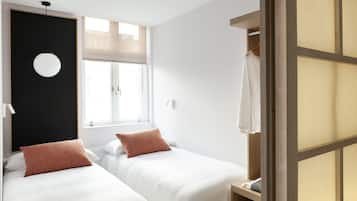Una camera da letto con due letti, una finestra, un armadio e un lampadario rotondo.