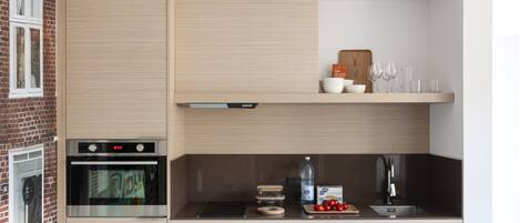 A modern kitchen with a built-in oven, a microwave, and a sink. There are wooden cabinets and a countertop with various kitchen items.