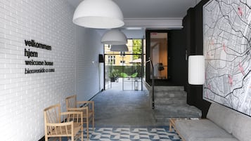 Un vestíbulo moderno con una pared de ladrillo blanco, un mural de mapa y un área de descanso con un tapete estampado.