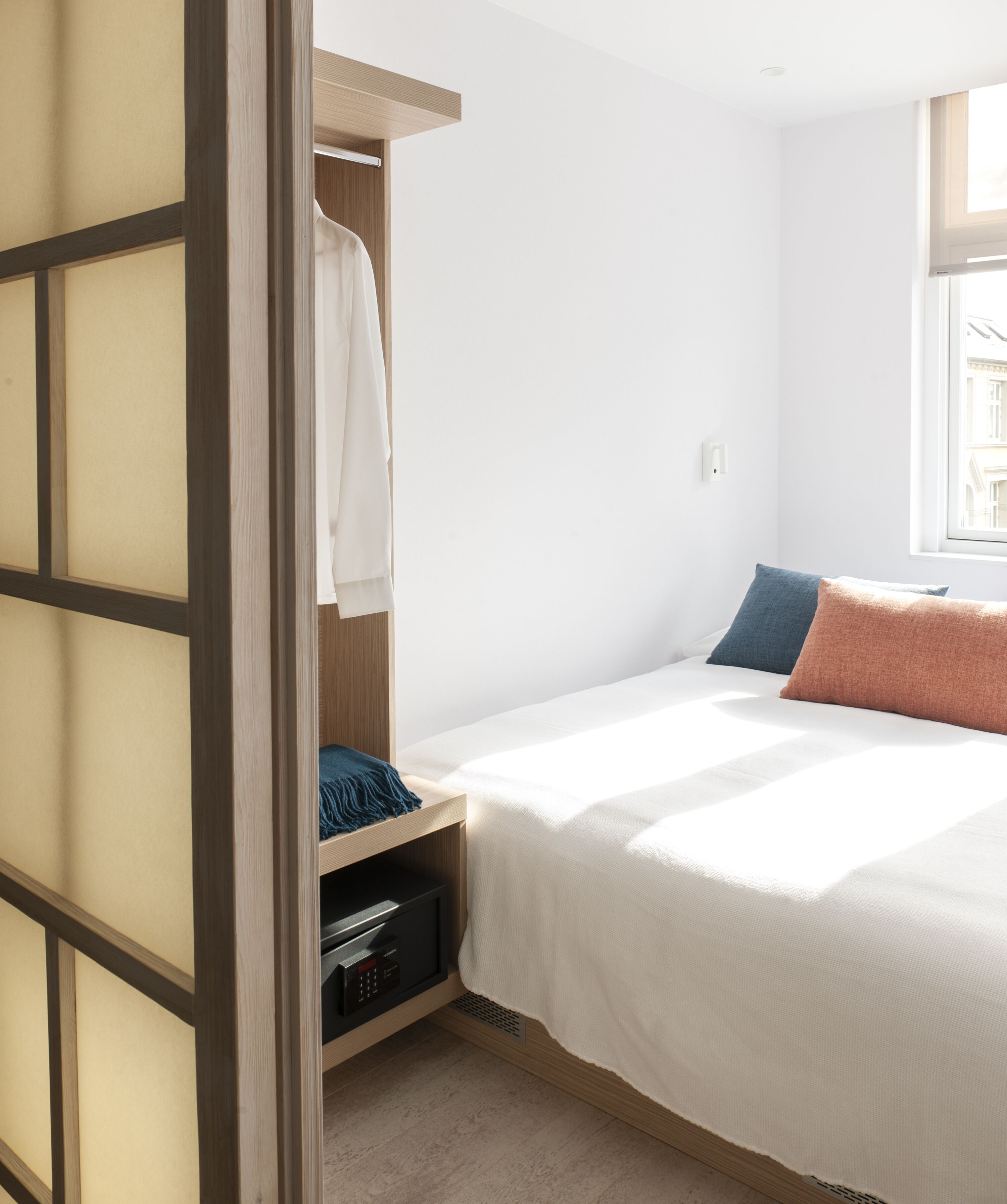 A bedroom with a bed, a wardrobe, and a window.