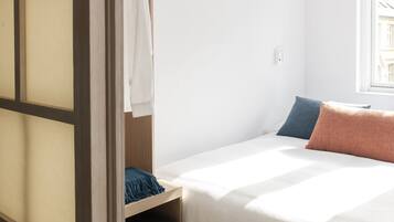 A bedroom with a bed, a wardrobe, and a window.