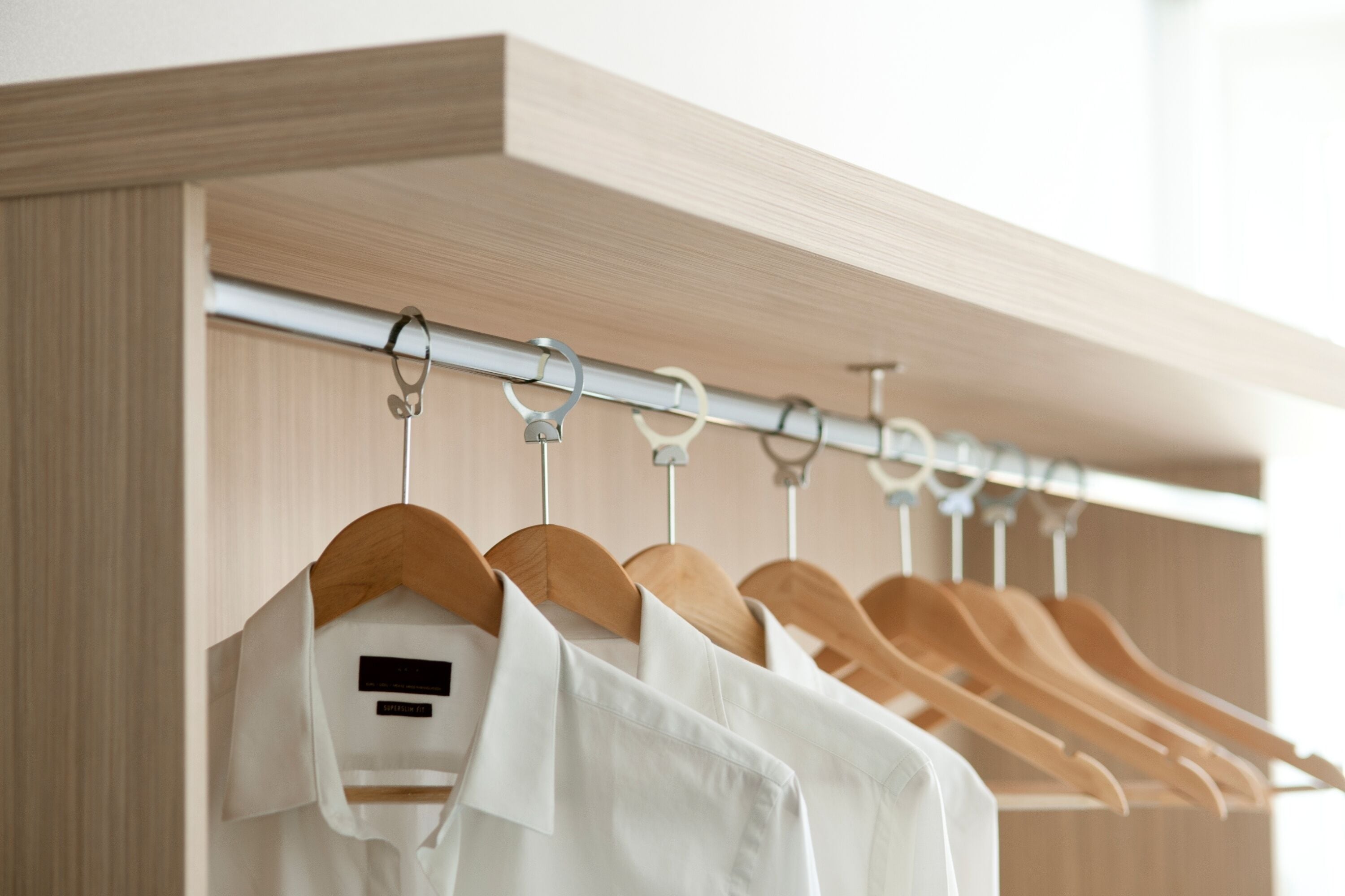 A closet with wooden hangers and a metal rod.