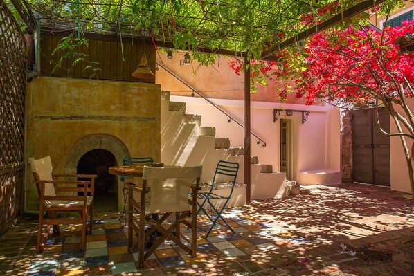 A courtyard with a tiled floor, a stone fireplace, and outdoor seating.