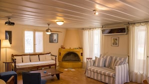 A cozy living room with a fireplace, two sofas, a coffee table, and a ceiling fan. - Lefkada's traditional house / cozy yard (Lefkada)