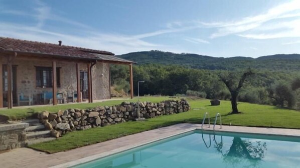 A house with a stone wall and a swimming pool.