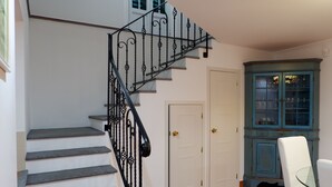 Un escalier avec des rampes en fer noir, une porte blanche et un meuble bleu avec des portes en verre.
