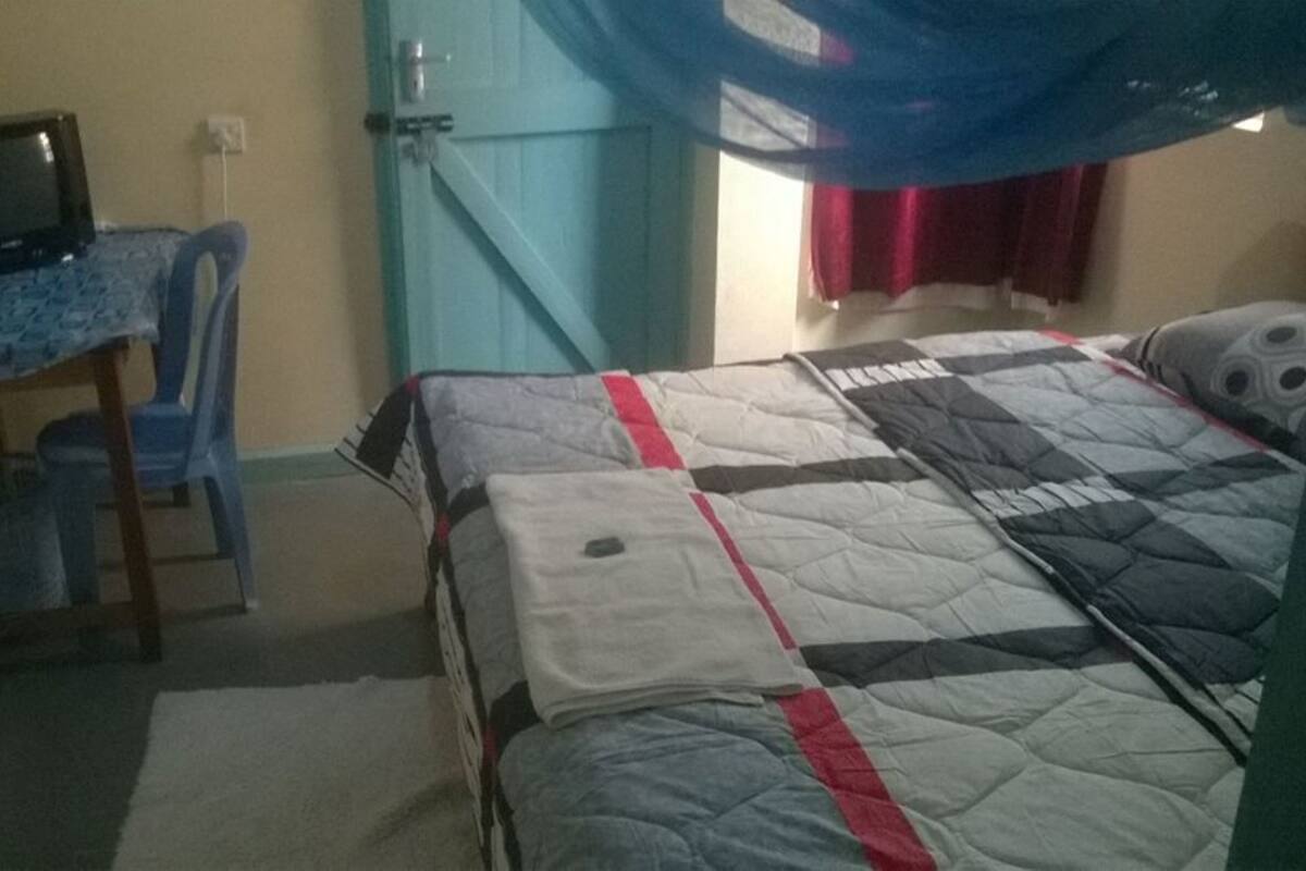 Une chambre à coucher avec un lit, un bureau avec un ordinateur et une chaise.