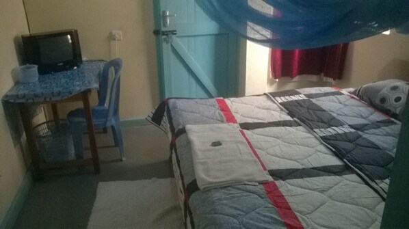 A bedroom with a bed, a desk with a computer, and a chair. - Lumo Blues Guest House (Kakamega)