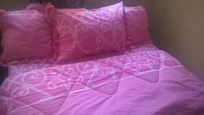 En säng med rosa sängkläder och ett mönstrat tyg.