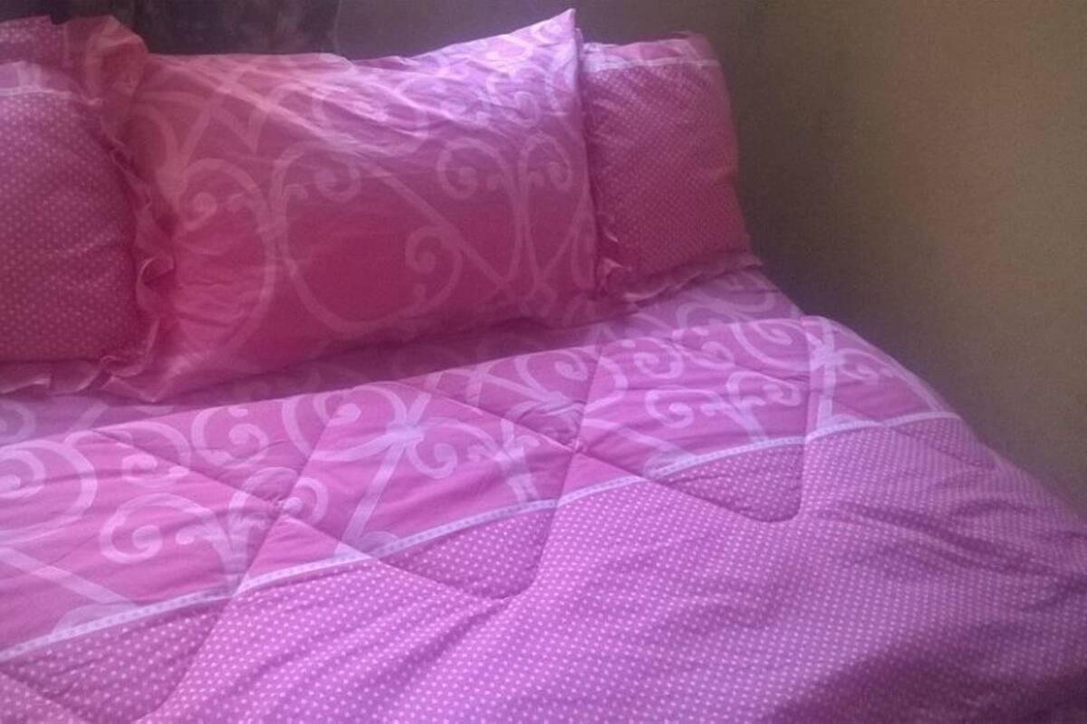 Un lit avec une literie rose et un motif décoratif.