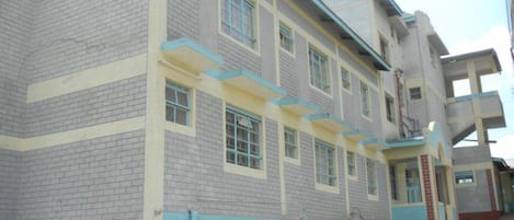 A multi-story building with a brick facade, multiple windows, and a flat roof.