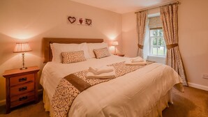 A neatly made bed with patterned pillows, a bedside lamp, and a wooden dresser.