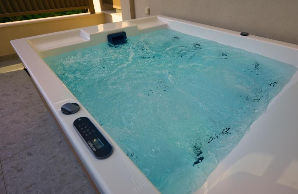 A hot tub with a control panel and a small seating area.