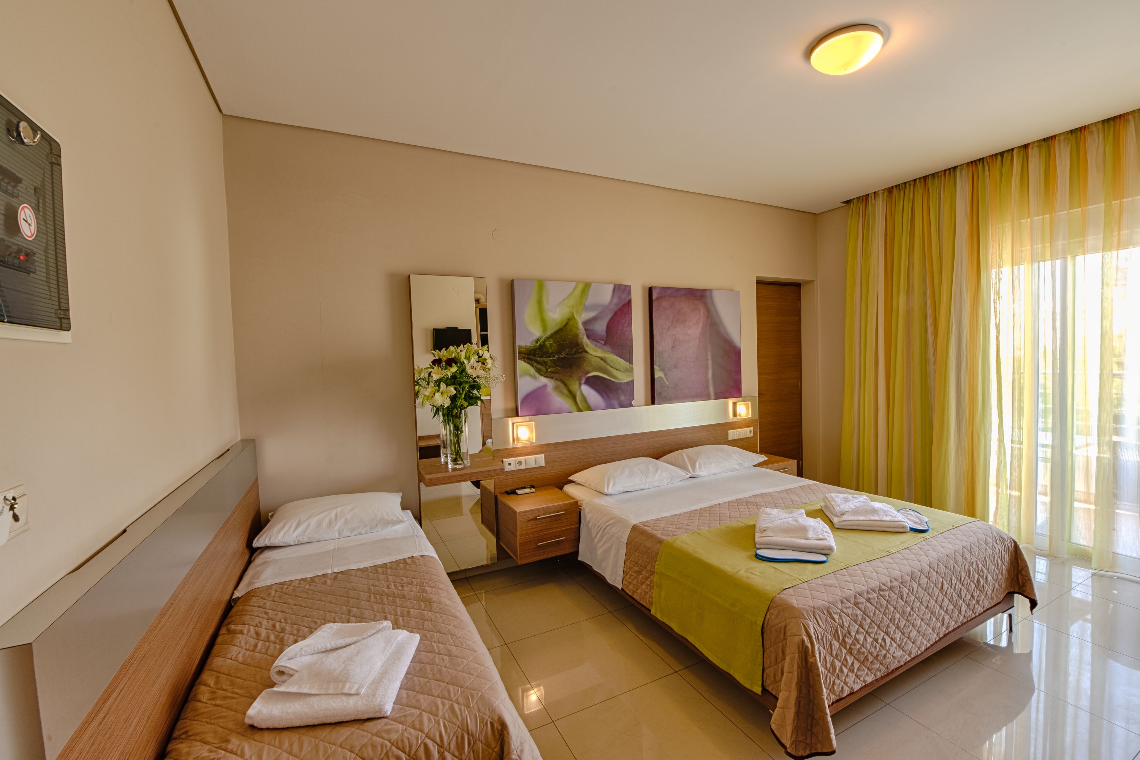 Ein Hotelzimmer mit zwei Betten, einem Nachttisch, einem Spiegel und Bildern an der Wand.
