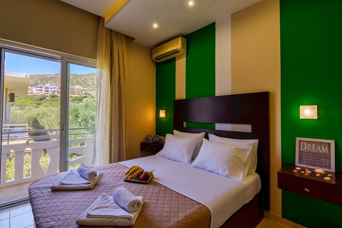Une chambre d’hôtel comprenant un lit, des oreillers, une table de chevet avec une lampe, une vue sur l’extérieur et un appareil de climatisation.