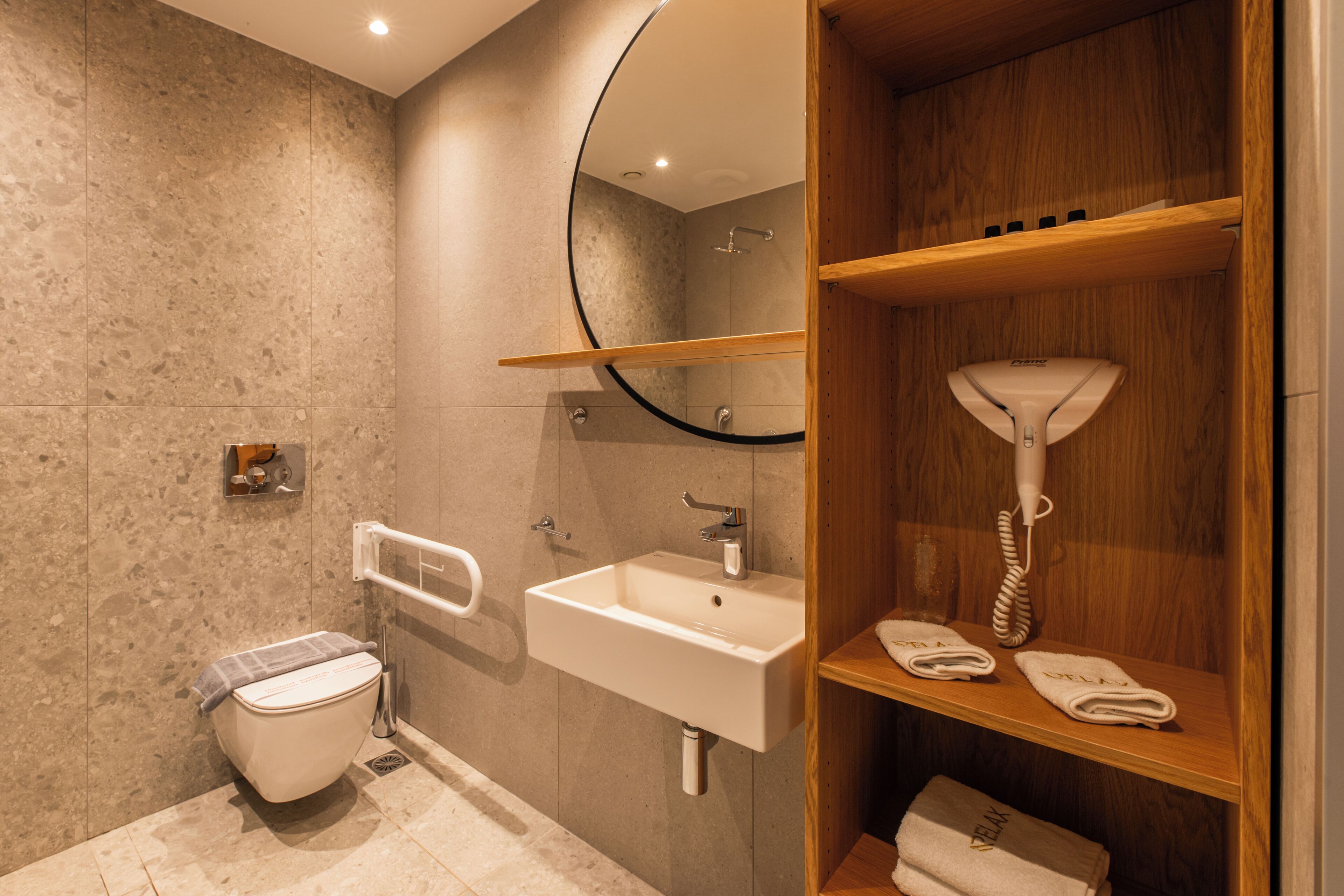 A modern bathroom with a toilet, sink, mirror, and towel rack.