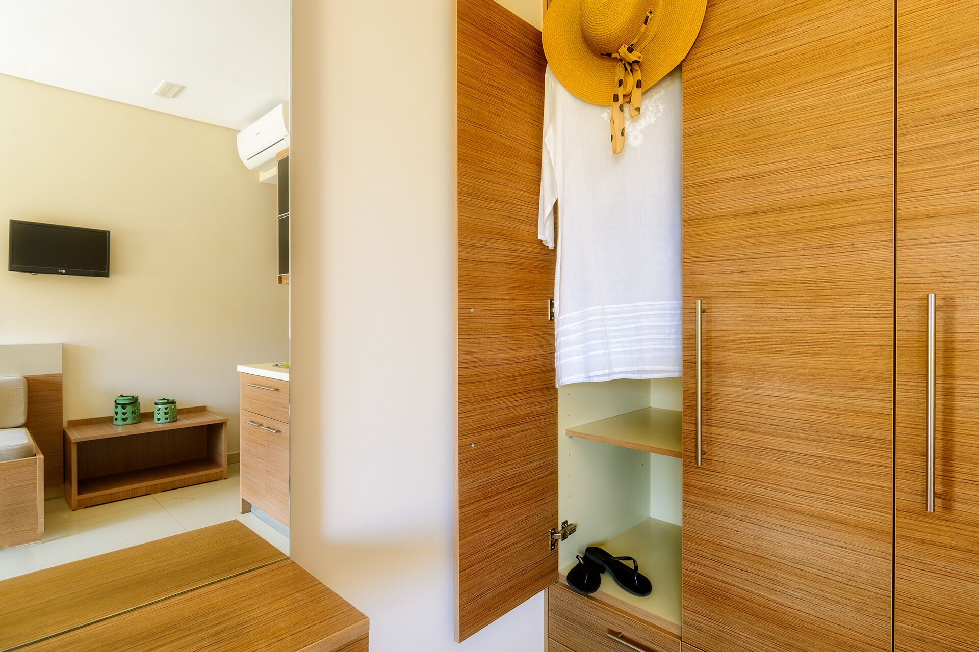 A modern bedroom with wooden furniture, a TV, and a wardrobe with a mirror.