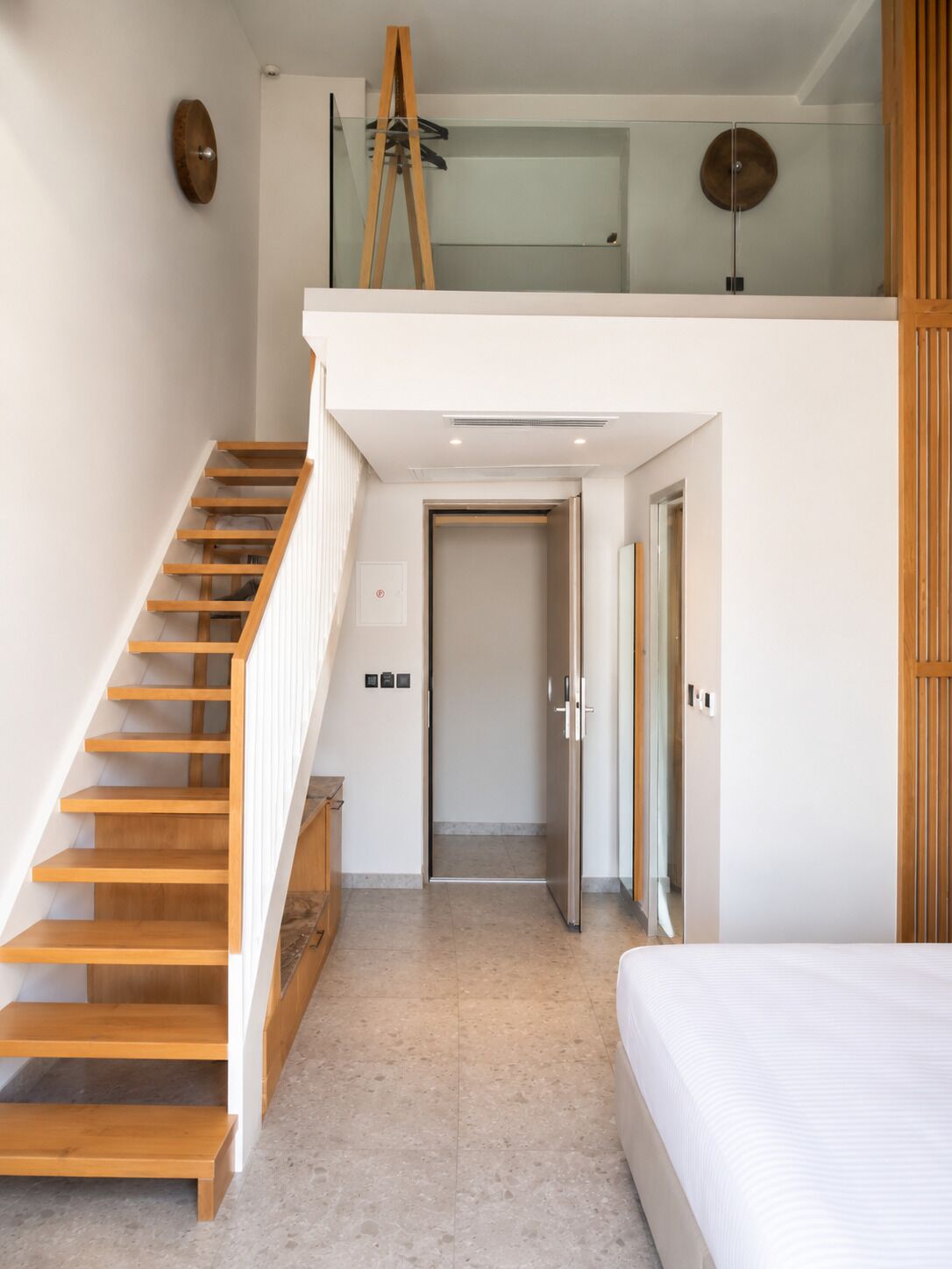 A modern interior with a wooden staircase, a loft bedroom with a glass ceiling, and a minimalist design.