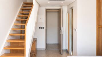 A modern interior with a wooden staircase, a loft bedroom with a glass ceiling, and a minimalist design.