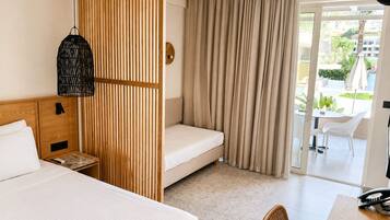 Habitación de hotel con cama, escritorio con teléfono, silla, ventana con cortinas y vista al exterior.