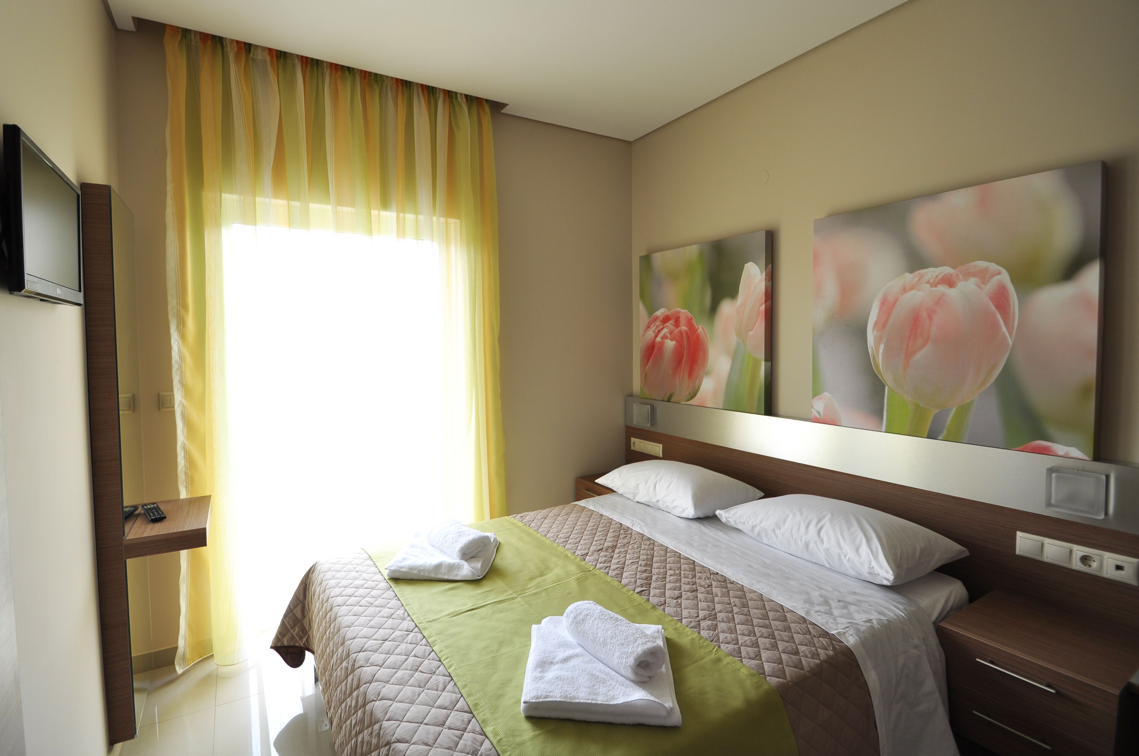 Ein Hotelzimmer mit Bett, Nachttisch, Fernseher und Bildern an der Wand.