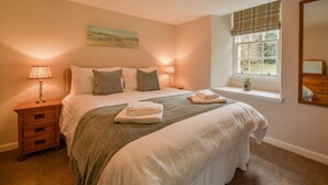 A neatly arranged bedroom with a bed, bedside lamps, a window with a view, and a mirror. - McDowell Cottage - Family Friendly Cottage on the Beautiful Blairquhan Estate (Maybole)