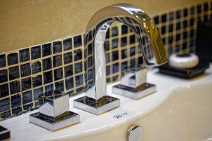 Un lavamanos con grifo cromado y un respaldo de azulejos.