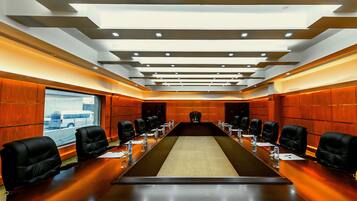 A conference room with a long table, black chairs, and a wooden panel wall.