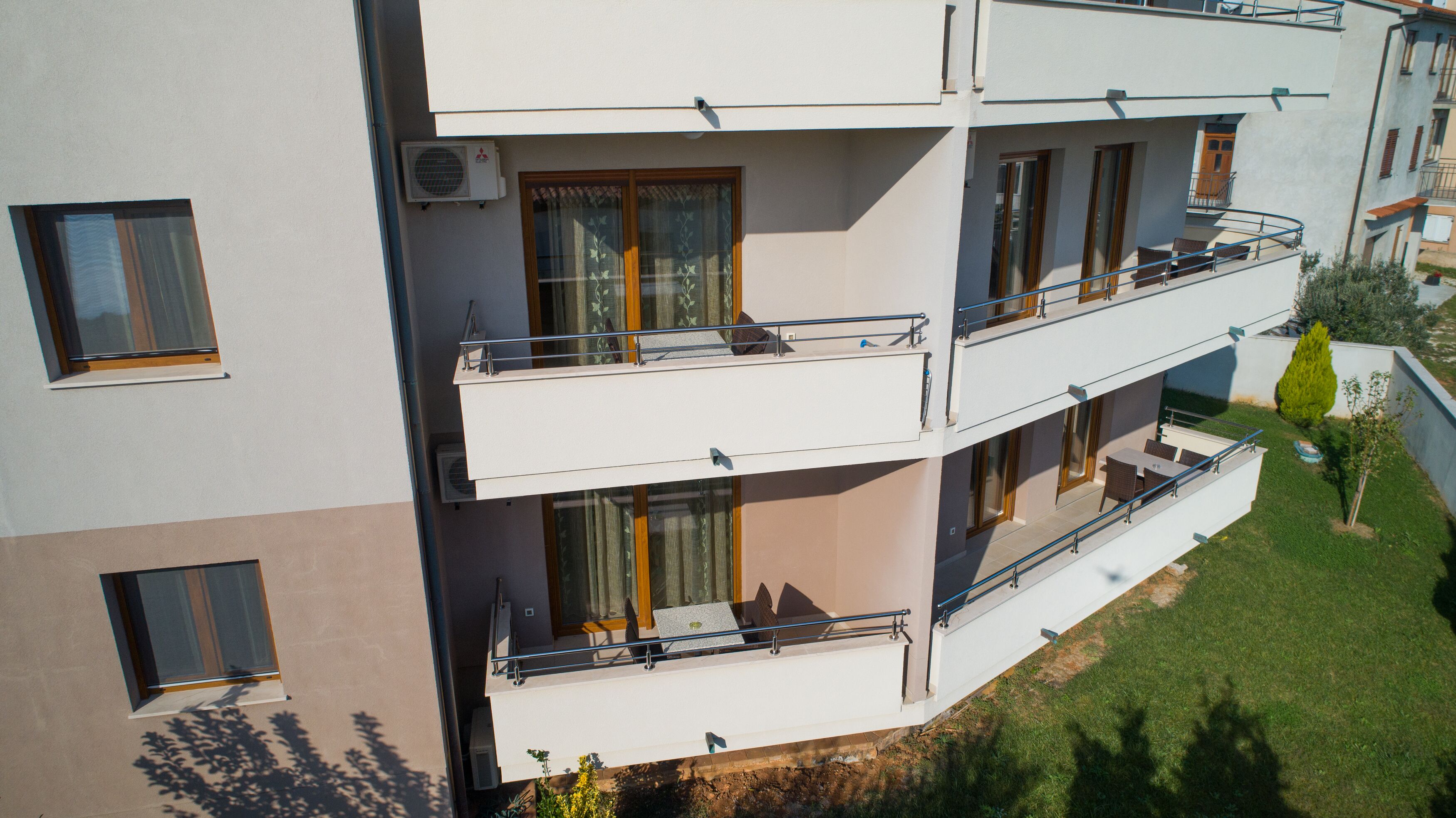 A multi-story building with balconies, large windows, and a small garden area.
