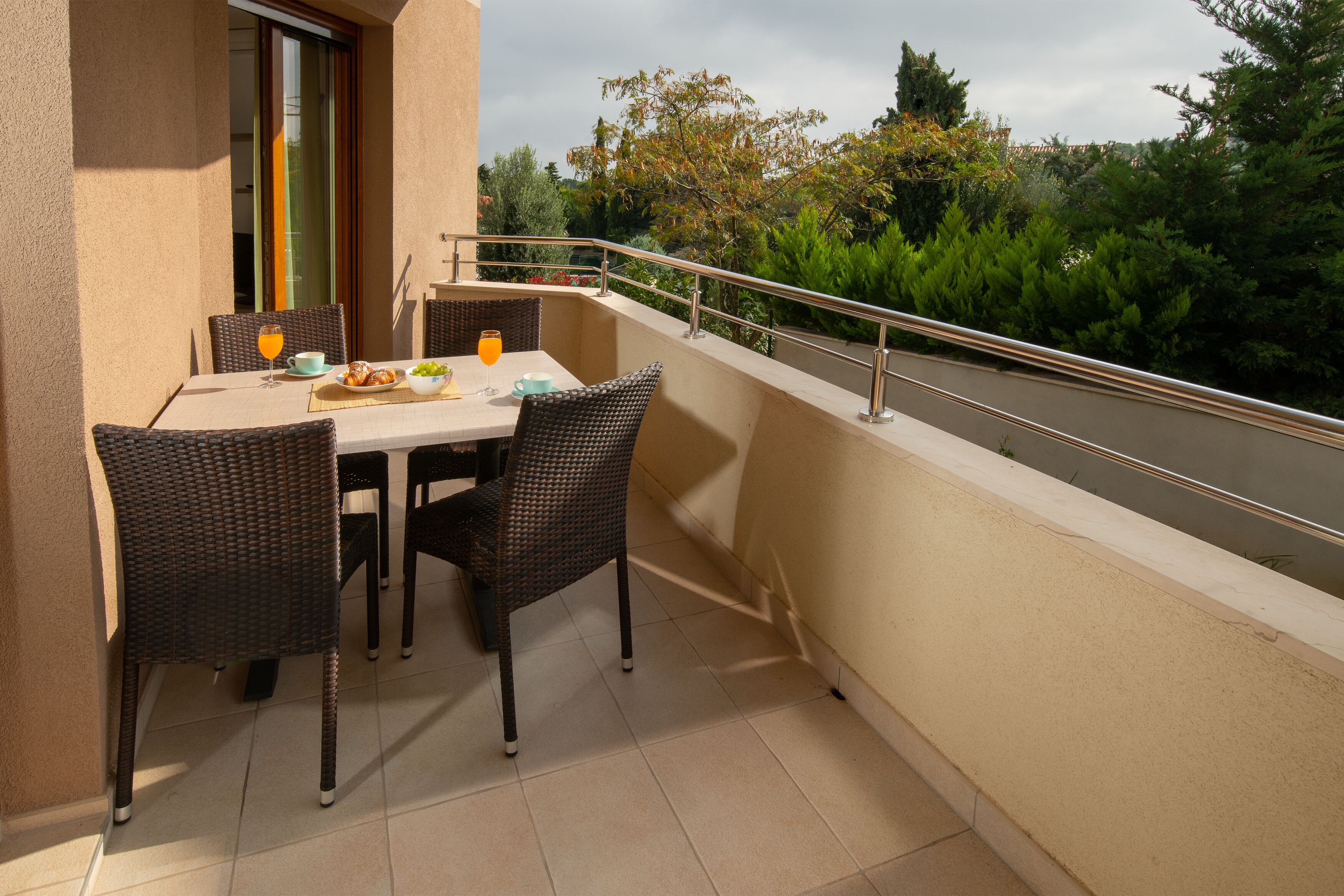 Ein Balkon mit einem Tisch für zwei Personen, Stühlen und einem Geländer.