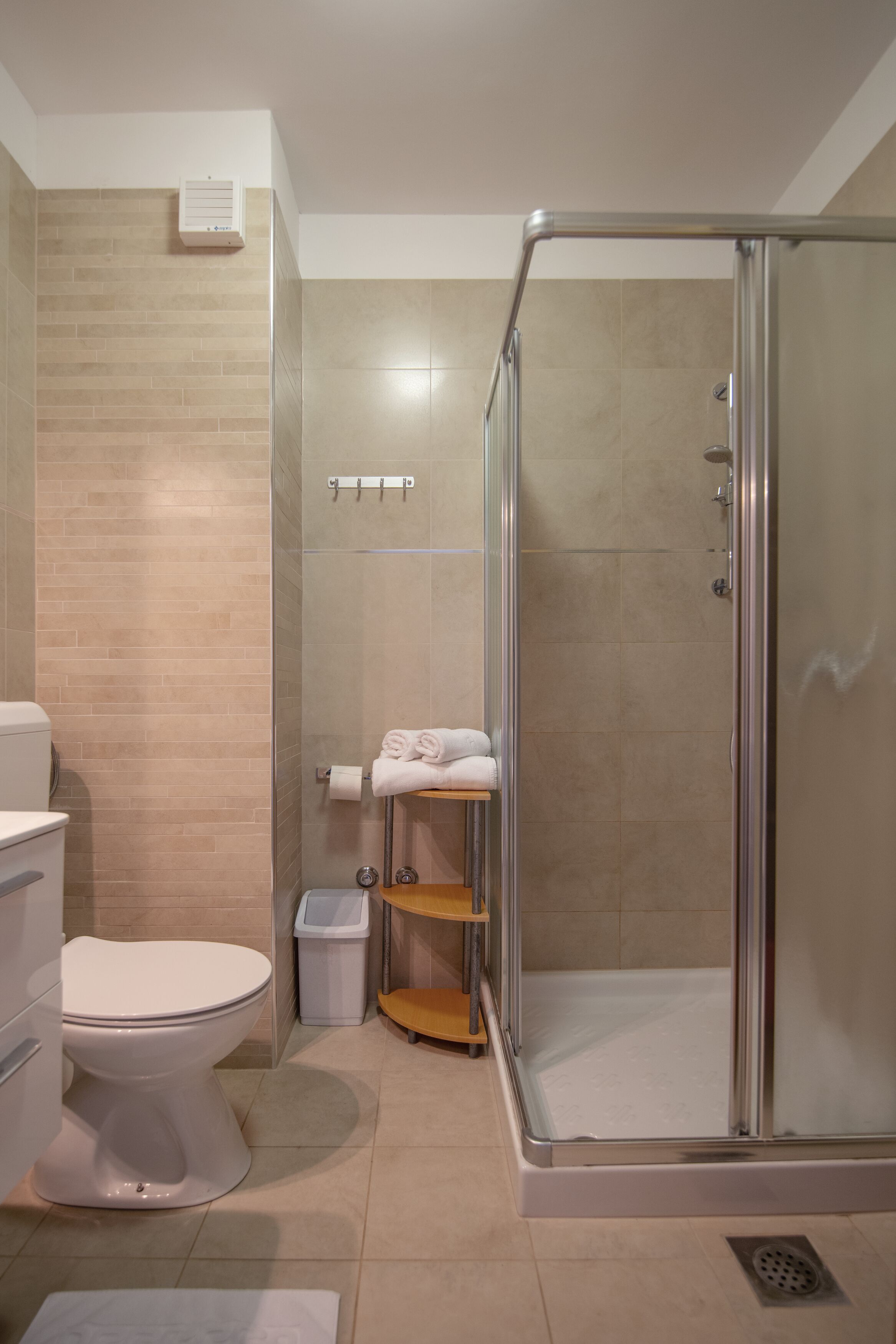 A modern bathroom with a glass-enclosed shower, a toilet, and a sink.