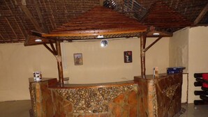 A wooden counter with a stone mosaic base, a clock on the wall, and a small shelf with items.
