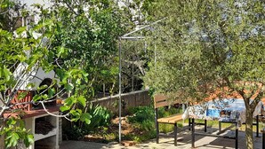 Une cour avec un banc, une pergola et une table recouverte de journaux.