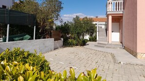Une cour avec un chemin pavé, une clôture en bois et un bâtiment doté d’un balcon.