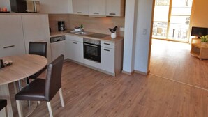 A compact kitchen with a dining area, a built-in oven, and a coffee maker. - Apartment for a perfect holiday with the family (Greifswald)