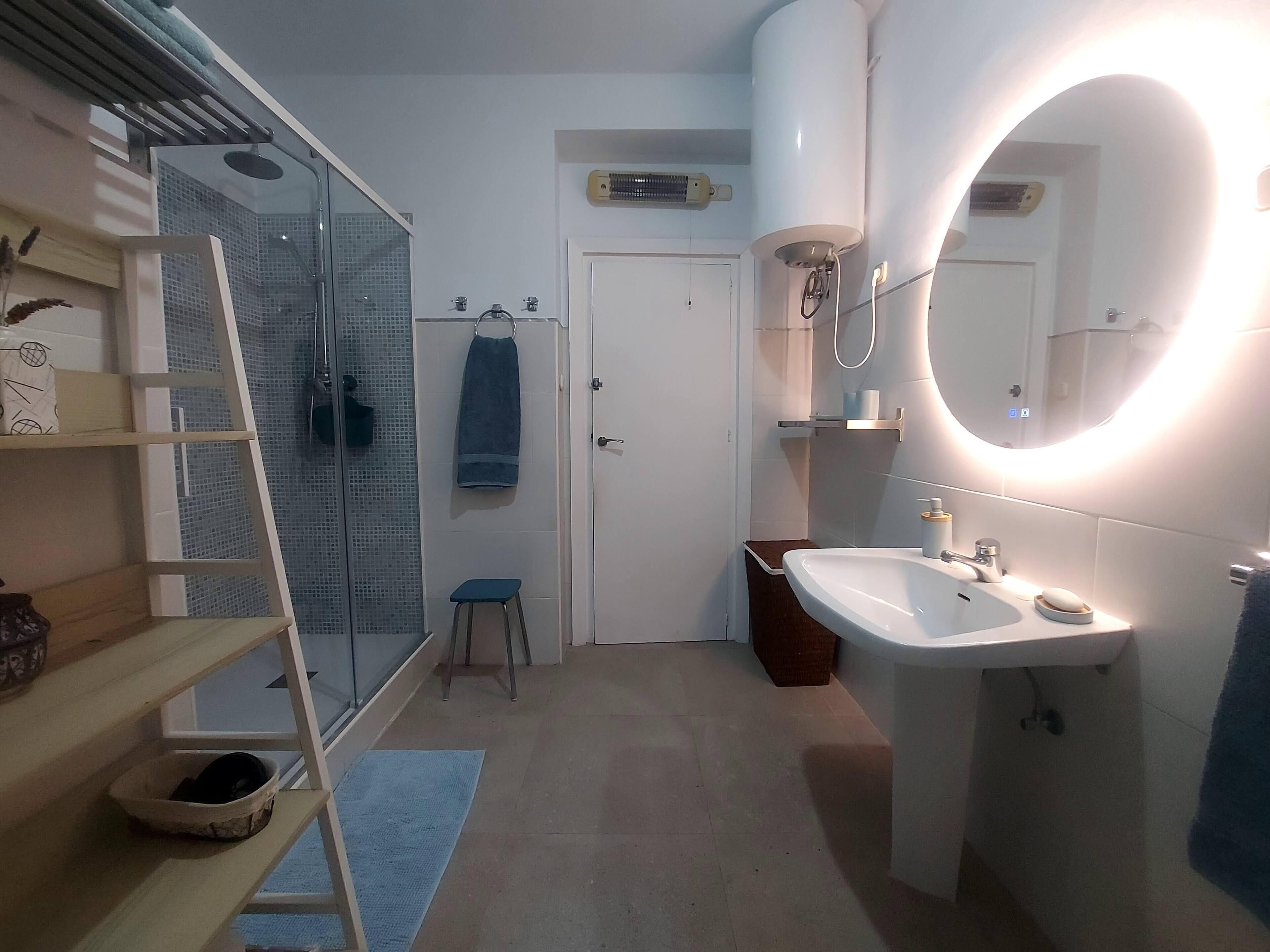 Ein modernes Badezimmer mit Glasdusche, Waschbecken mit Spiegel und Handtuchhalter.