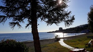 A coastal path leading to a beach with a clear view of the sea and a distant hill with a structure. - Beautiful house with garden 3 minutes from the beach (Almuñécar)
