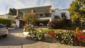 A two-story house with a balcony, surrounded by a garden with flowering plants. - Beautiful house with garden 3 minutes from the beach (Almuñécar)