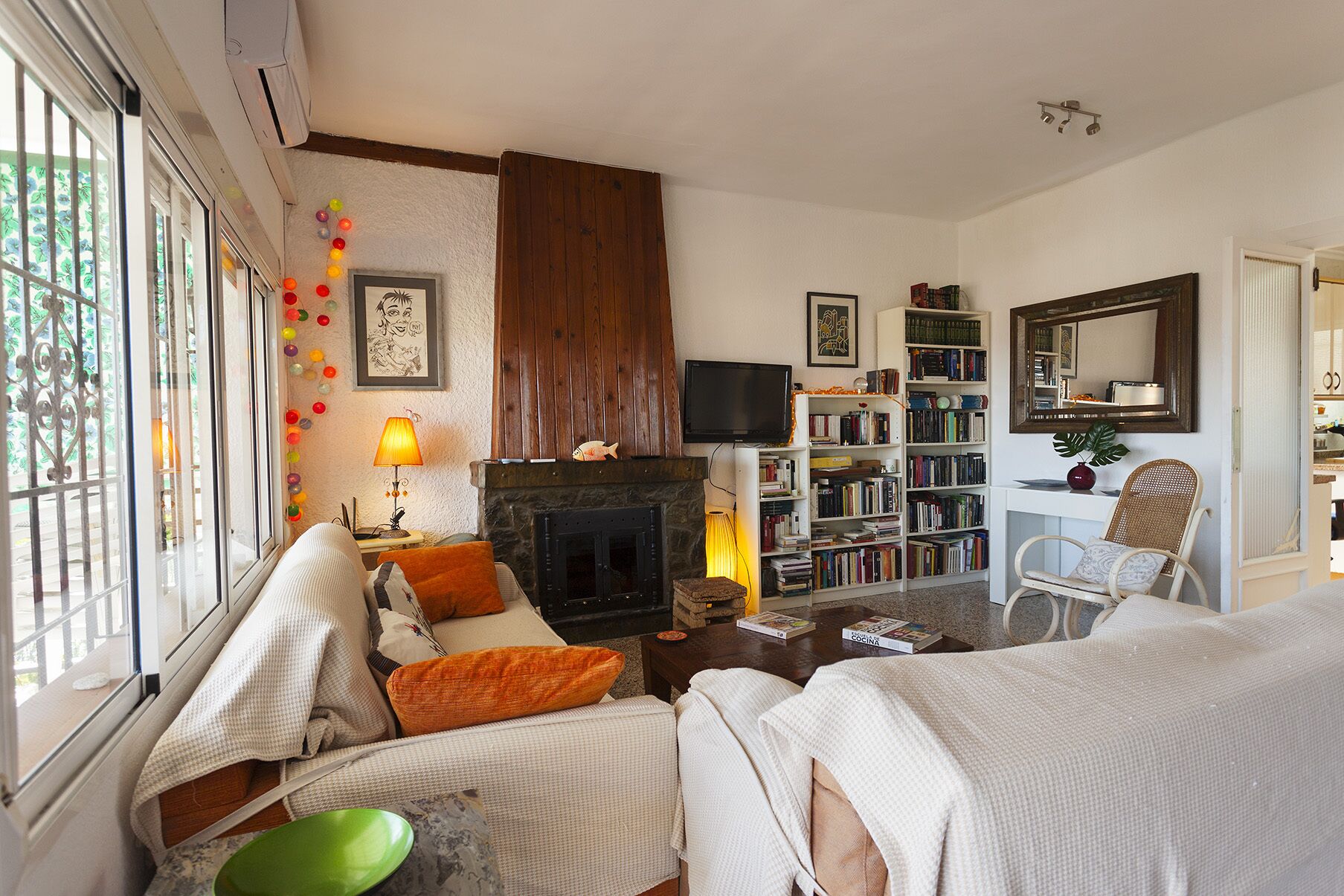 Una sala de estar acogedora con chimenea, estantería, televisor y un área de descanso confortable.