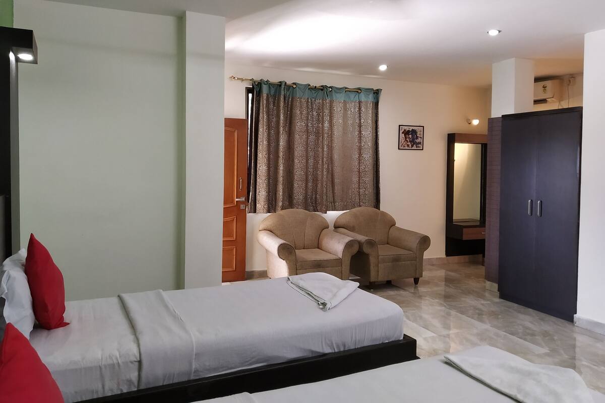 Quarto com cama, uma cadeira, guarda-roupa e porta para outro cômodo.